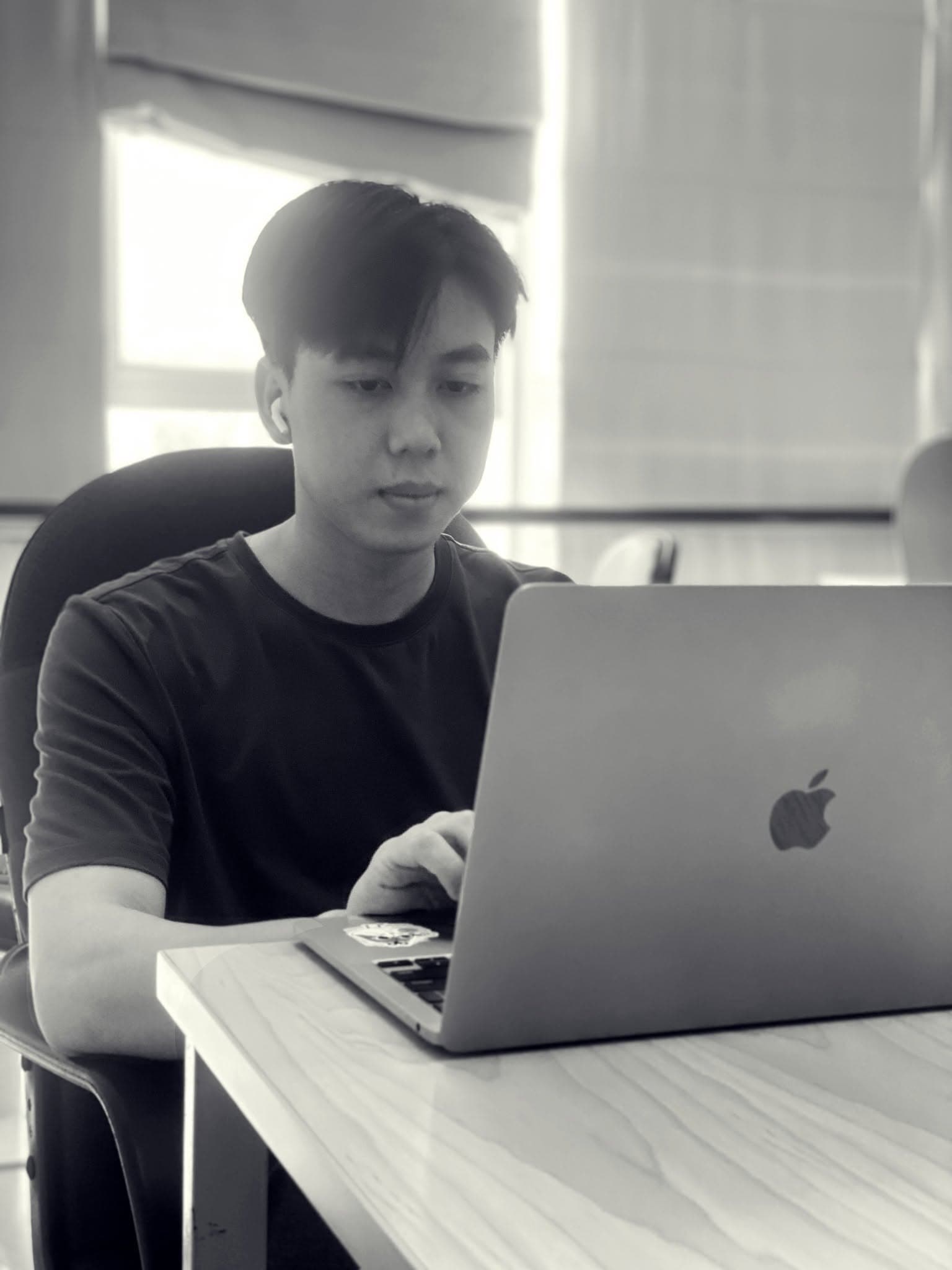 Michael in a black shirt working at a MacBook, in a black-and-white portrait