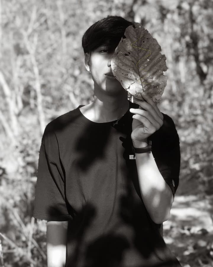 Duy holding a leaf in a black-and-white portrait
